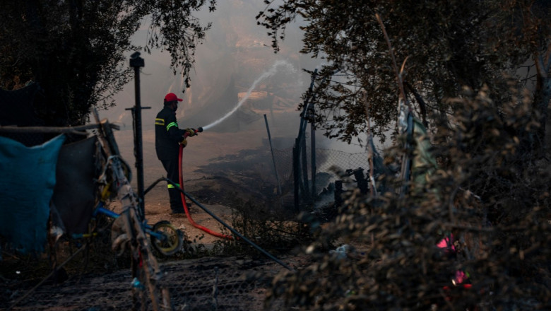 pompier care stinge un incendiu într-o tabără de refugiați din Grecia.