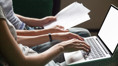 Couple holding reading documents at home with laptop, close up