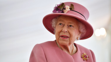 Regina Marii Britanii într-un costum roz cu pălărie ornată cu flori.