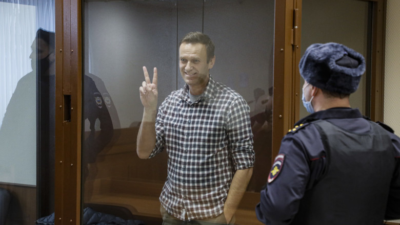 alexei navalnii zambeste si face semnul V din cusca de sticla in sala de judecata, unde e pazit de politisti