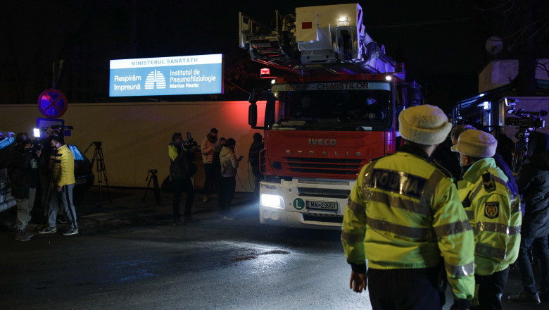 masina de pompieri iesind pe poarta institutului marius nasta din bucuresti si doi politisti care o privesc