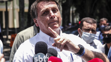 Jair Bolsonaro, cu microfoane în față, gesticulează cu degetul arătător.