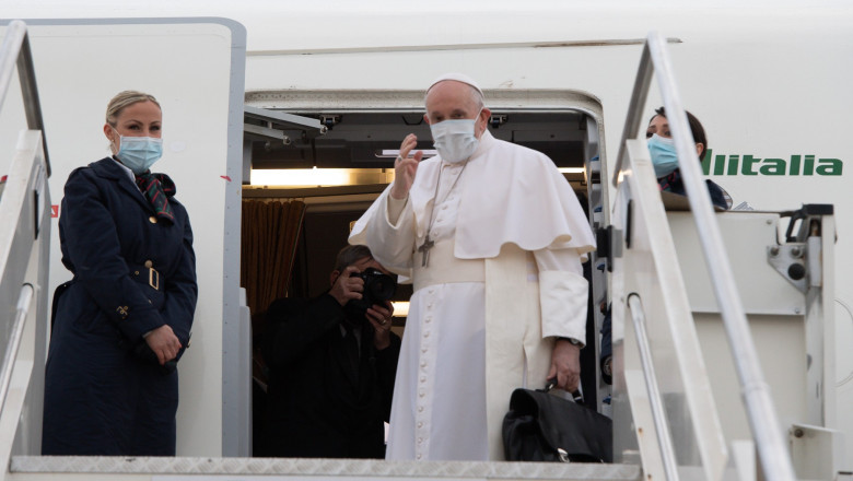 Papa Francisc la intrarea în avionul care îl duce spre Irak. În dreapta sa stă una dintre însoțitoarele de zbor.