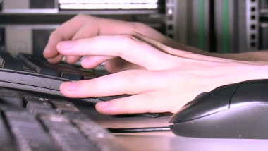 O persoană scrie la tastatura computerului.