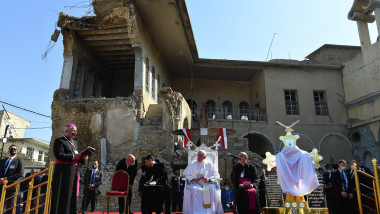 papa sta jos inconjurat de clerici in curtea interioara a unei biserici din mosul