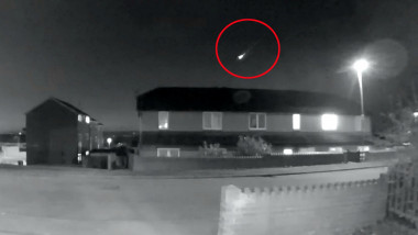 Imagine alb negru cu case și un meteorit care străbate cerul