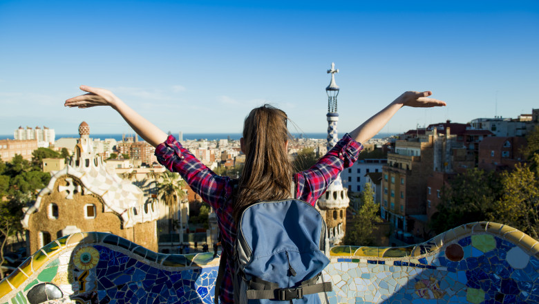 tanara care face un gest larg cu bratele in timp ce priveste panorama orasului barcelona