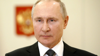 Vladimir Putin cu steagul și stema Rusiei pe fundal.