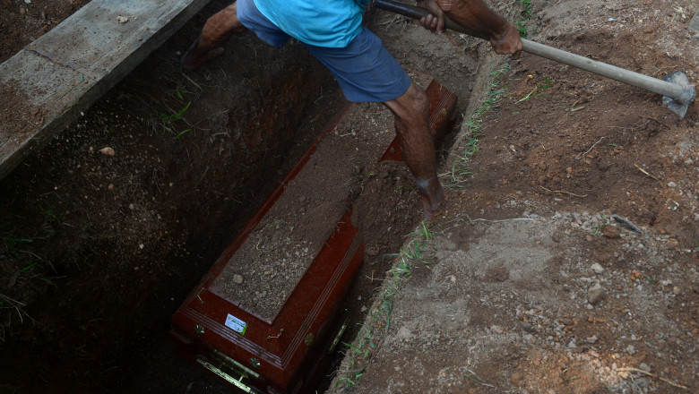 Un gropar din Sri Lanka acoperă un sicriu cu pământ
