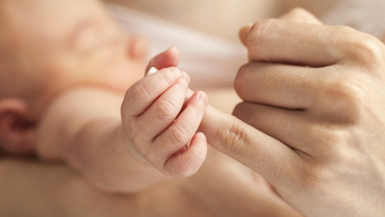mana unui bebelus care tine degetul mamei
