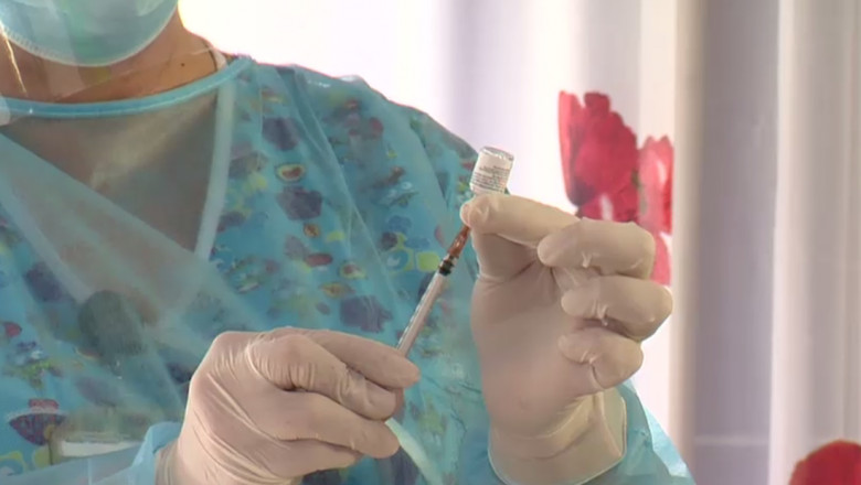 O asistentă medicală umple o seringă cu serul dintr-o doză de vaccin.
