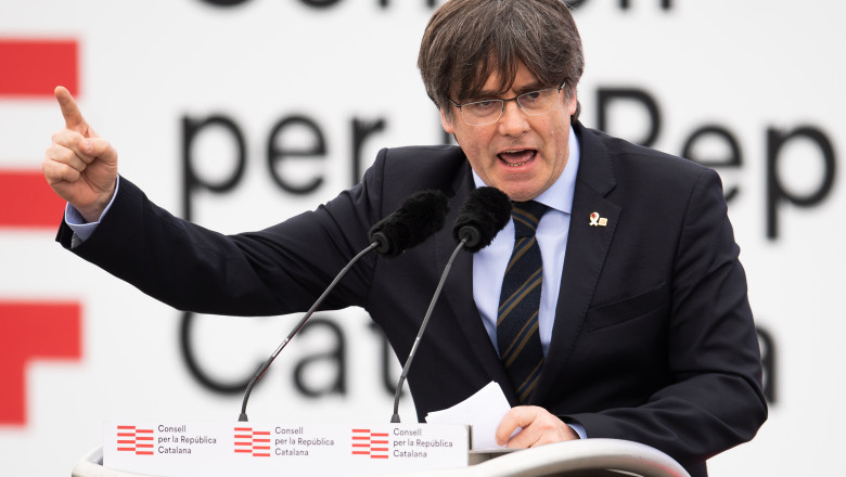 Carles Puigdemont vorbește la microfon și gesticulează cu mâna