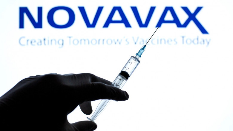seringa cu vaccin in fata unui panou cu logoul novavax