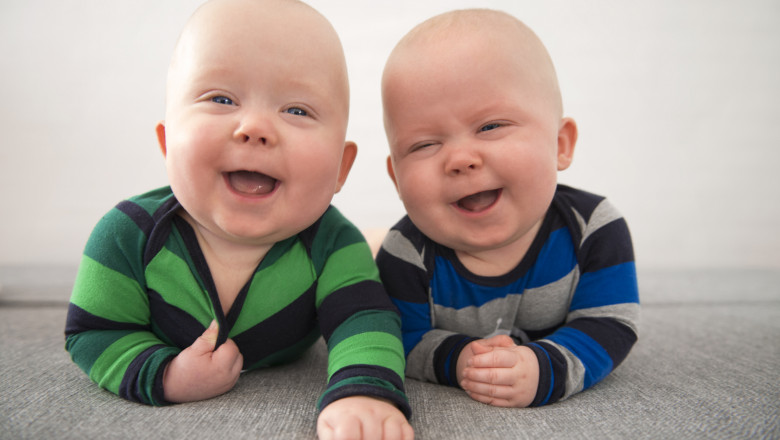 Copii gemeni identici râd în timp ce stau pe jos