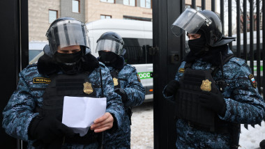 politisti rusi de la trupele speciale, cu echipament de protectie si casc, verifica o lista cu invitati