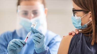O asistentă vaccinează o tânără.