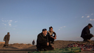 membri ai minoritatii uigure din china fotogafiati in genunchi pe un camp