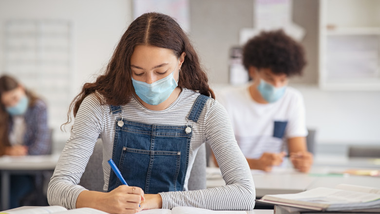 elevi de liceu cu masti protectie sustinand o proba scrisa