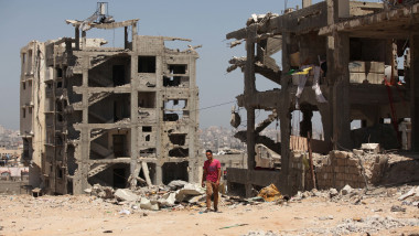 Palestinieni în faţa unor clădiri distruse în Gaza, după atacurile armatei israeliene din 2014.