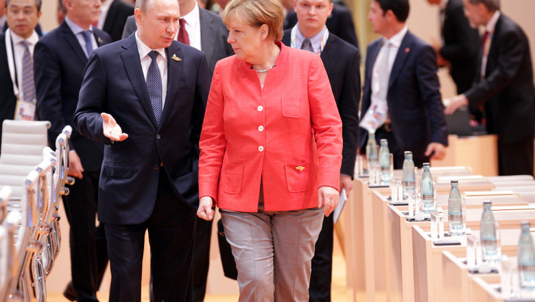 Angela Merkel discută cu Vladimir Putin, mergând între două mese