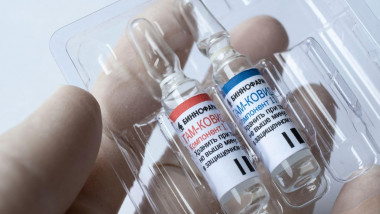 Două doze de vaccin Sputnik V ținute de un asistent medical în mână.