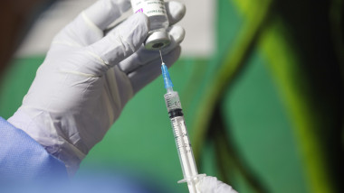 O asistentă medicală umple seringa cu ser de vaccin.