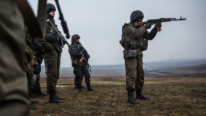 Mai mulți militari ucraineni, unul dintre ei ochește cu o pușcă.