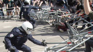 politisti echipati cu casti de protectie trag de garduri metalice daramate
