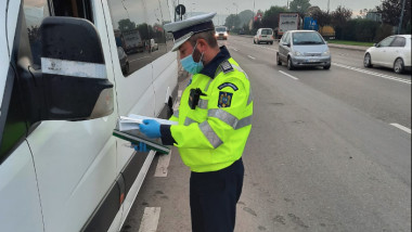 un politist verifica actele unui sofer de microbuz.