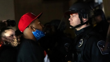 Un bărbat de culoare și un polițist se privesc în timpul unei confruntări
