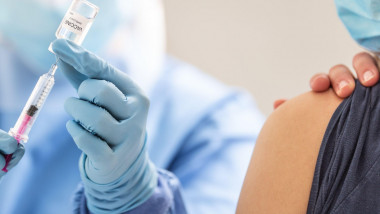 O femeie este vaccinată de către un cadru medical.