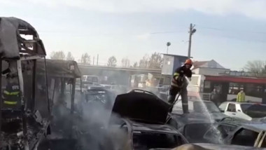 Un pompieri stinge mașini care ard.