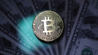 Monedă Bitcoin în dreptul unor bancnote de dolari.