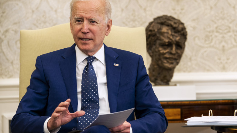 Joe Biden stă pe scaun cu o foaie în mână