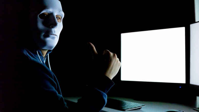 barbat cu o masca alba pe fata in fata unui computer si cu degetul mare ridicat