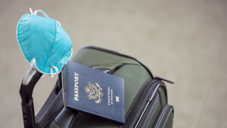 pasaport sua alaturi de o geanta de voiaj si o masca de protectie