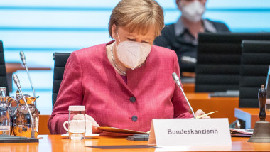 Angela Merkel se uită pe niște documente într-o sală de ședințe.