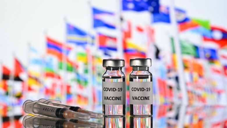 ilustratie cu doze de vaccin covid si stegurile tuturor tarile de pe glob pe fundal