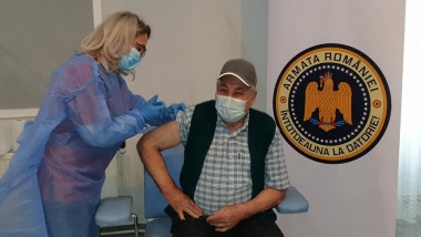 un batran cu masca este vaccinat intr-un spital militar