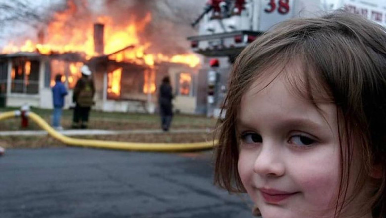 o fetiță în fața unei clădiri în flăcări, cu un zâmbet diabolic pe față.