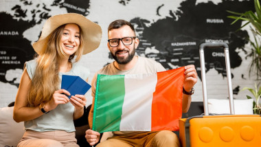 turisti cu bagaj si steagul italiei in mana