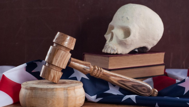 Un steag al SUA, două cărți pe care stă un craniu și un ciocănel de judecător