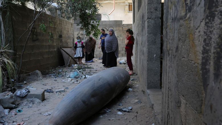 palestinieni se uita la o bomba neexplodata cazuta pe strada lor