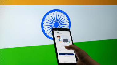 Aplicația cu ajutorul căreia locuitorii din Mumbai pot câștiga un loc la vaccinare împotriva Covid pe ecranul unui telefon mobil, în fundal steagul indiei