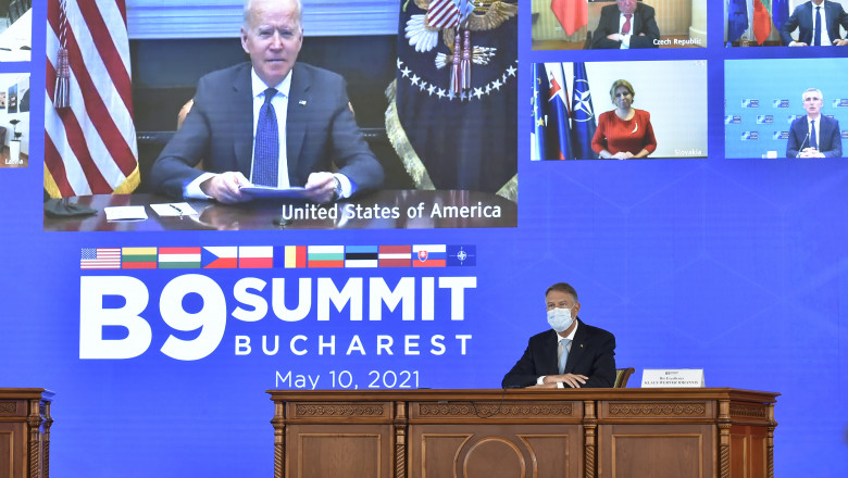 joe biden apare pe un ecran mare in timp ce se adreseaza participantilor la summitul B9. Dedesubt e un prezidiu in care sta klaus iohannis