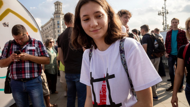 Fată tânără, cu un tricou alb cu imprimeu, în mijlocul unui grup de oameni la un protest din Rusia
