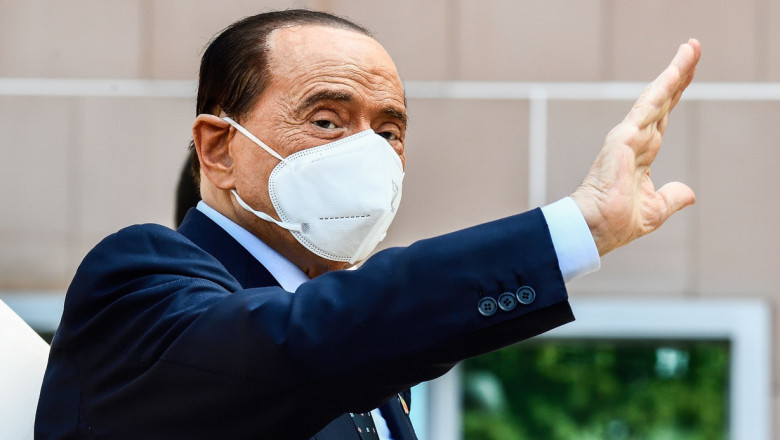 Silvio Berlusconi face un semn de salut.