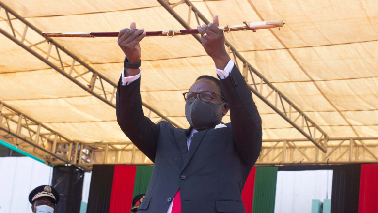 Lazarus Chakwera, președintele statului Malawi, cu masca si ochelari, ridica o sa bie de ceremonie in cadrul unei festivitati