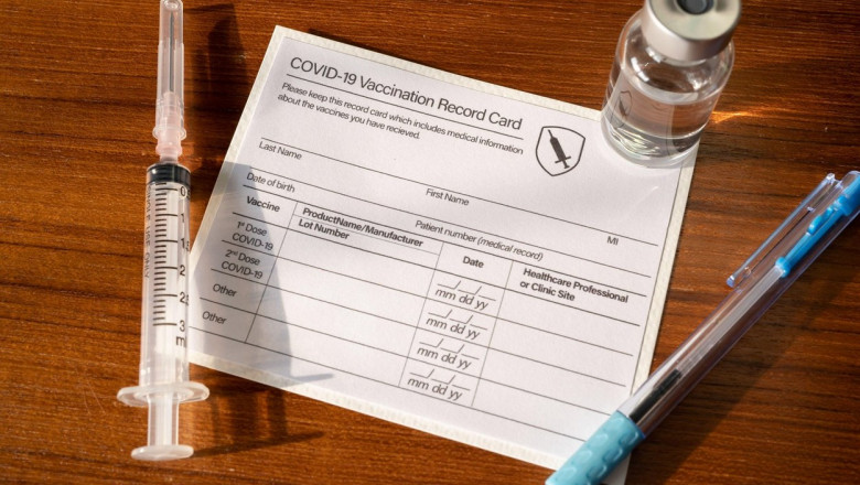 certificat de vaccinare pe hartie, langa o doza, o seringa si un pix