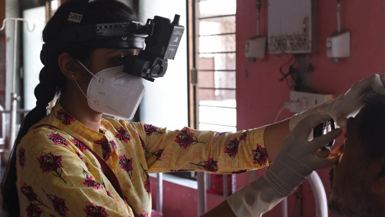 Femeie cu mască de protecție și echipament oftalmologic examinează un pacient
